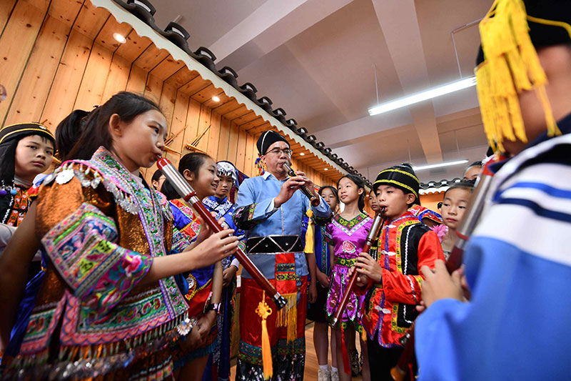 10月27日,在广西融安县第二实验小学,师生们在吹奏民族乐器—巴乌.