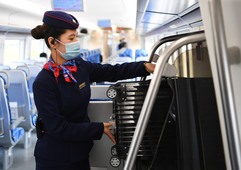 10月26日,郑机线城际列车上的乘务员帮助乘客摆放行李箱.